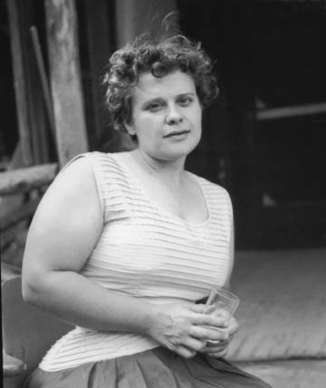 Black and white photo of a young white woman (Hazel Larsen) with short curly hair wearing a pale tank top posing for the camera.
