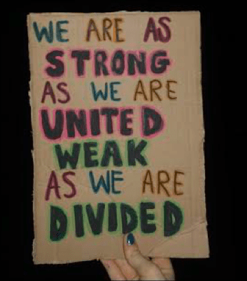 A hand holds up a placard which reads 'we are as strong as we are united; weak as we are divided'