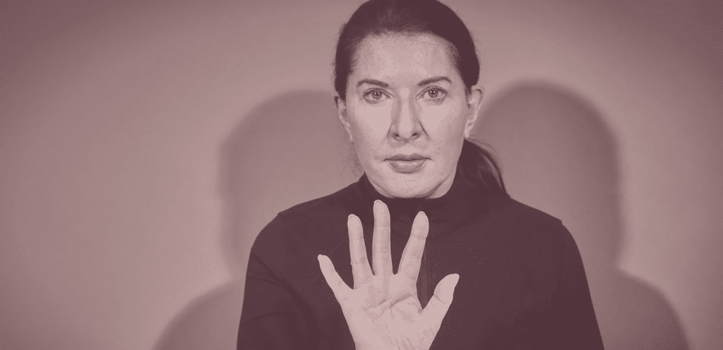 Photo of Marina Abramovic with her palm held up facing outwards.