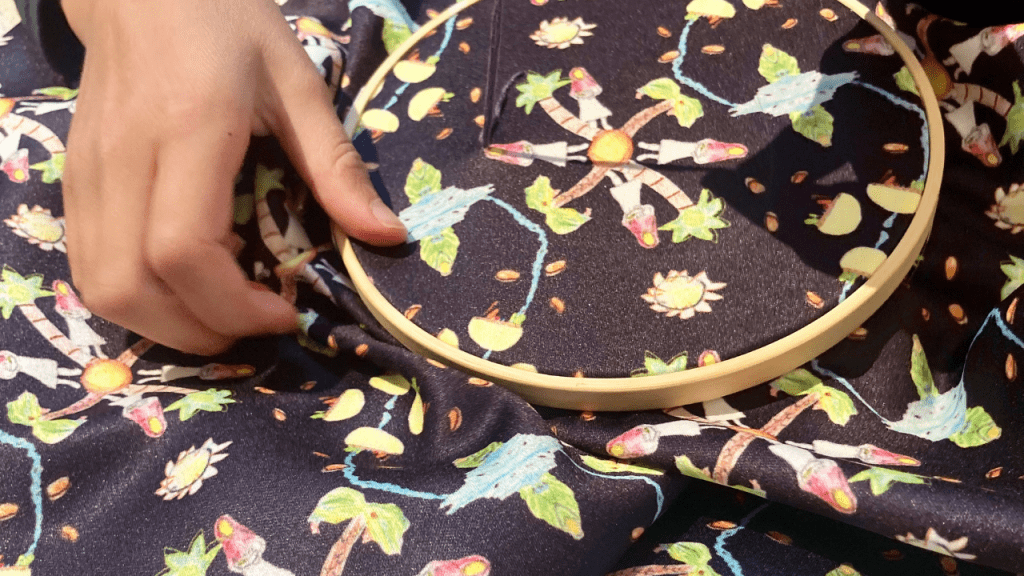 A child embroiders on patterned fabric, displayed in the Back Toward Oneness exhibition.