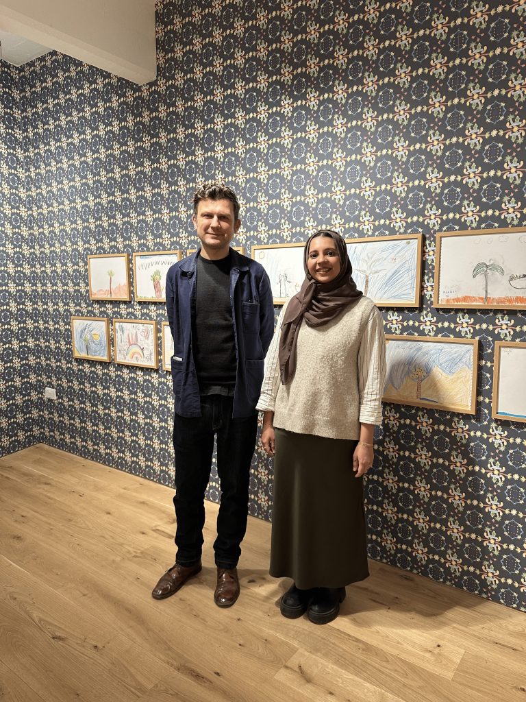 Dominik Czechowski and Farwa Moledina smile in the exhibition, Back Toward Oneness.